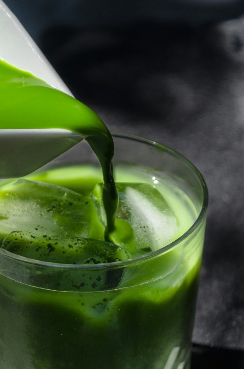 Boisson verte versée sur des glaçons dans un grand verre transparent