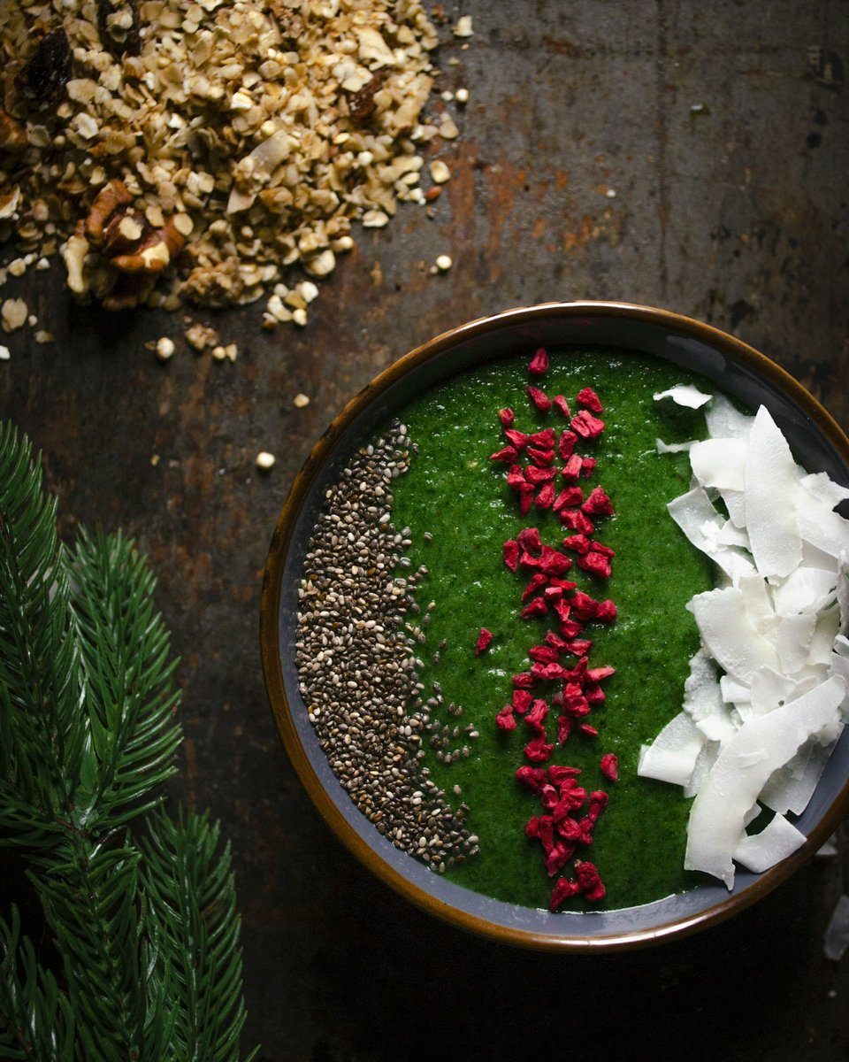 Bol garni d'une préparation vert foncé, parsemé de graines et de copeaux de noix de coco