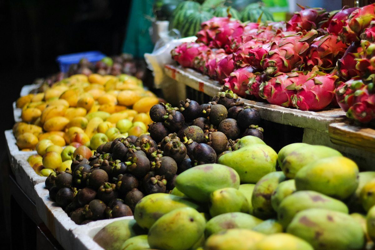 Étal de marché chargé de fruits tropicaux colorés empilés