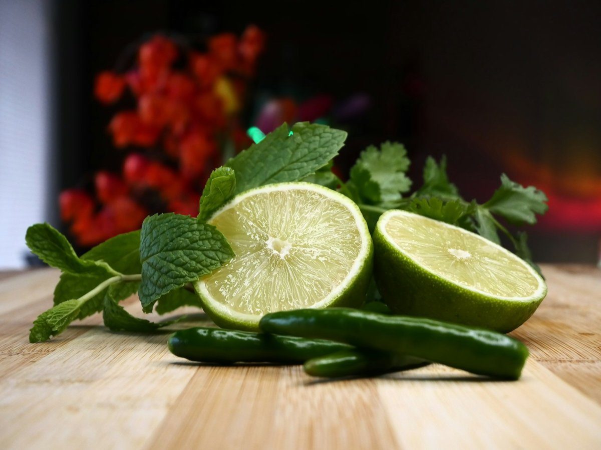 Citrons verts coupés, piments et feuilles de menthe sur une planche